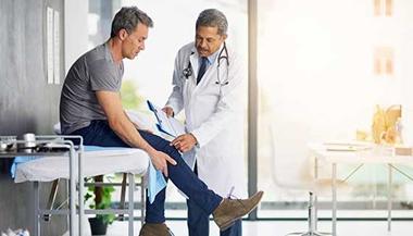 Man discussing knee pain with doctor.