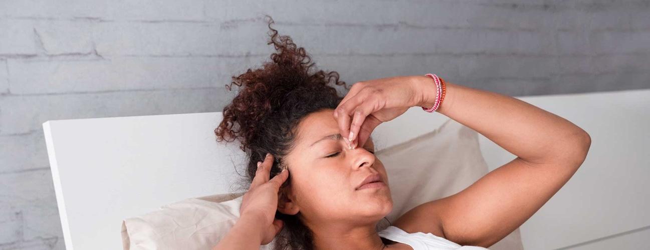 Woman lying in bed experiencing a migraine