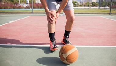 一个篮球运动员疼得抓着膝盖