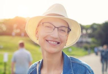 Bald woman smiling and wearing a sun hat