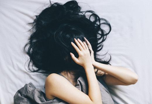 一个女人躺在床上，用头发遮住脸.