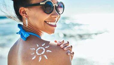woman smiles with sun drawn in lotion on shoulder