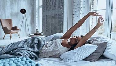 Woman waking up and stretching in bed