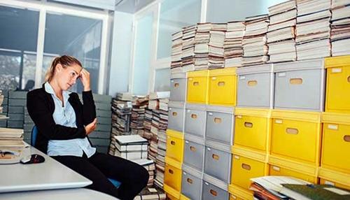 工作压力大的女人看着满满的文件柜