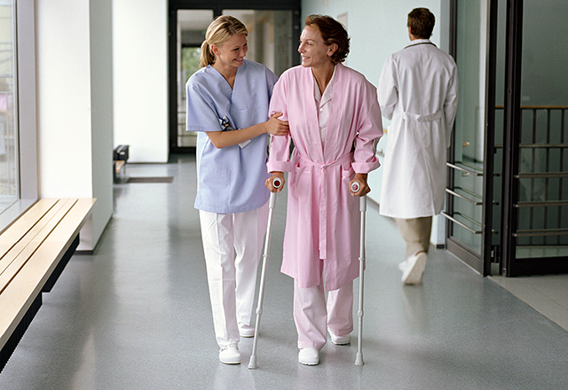 woman helping a patient walk in the hallway